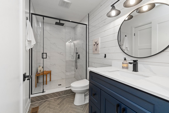 Bathroom with navy vanity and walk-in rain shower at Casa Muzyka Lakehouse