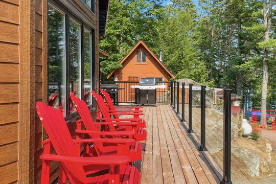 Red Muskoka chairs and BBQ on the lakeside deck at Casa Muzyka Lakehouse, Barry's Bay