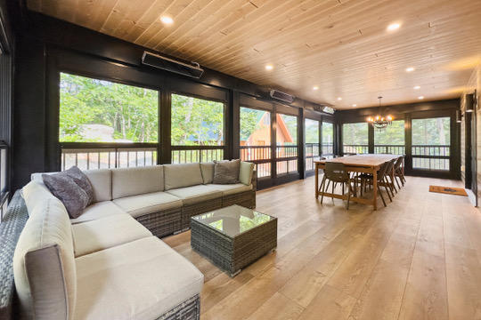 Muskoka room lounge with wicker sectional overlooking the forest at Casa Muzyka Lakehouse
